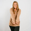 Woman wearing tan IV zip hoodie with front zipper, smiling in lifestyle portrait.