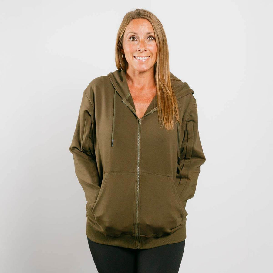 Woman wearing olive green IV zip hoodie with front zipper, standing against white background.