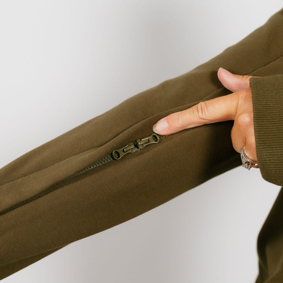 Woman wearing olive green IV zip hoodie, close-up of left sleeve zipper access feature.