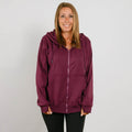 Woman wearing a burgundy zip-up hoodie with black pants smiling at camera.