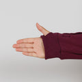 Person's hand extended from a burgundy zip hoodie with ribbed cuff against gray background.