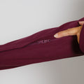Hand pointing to a small zipper detail on the sleeve of a burgundy zip hoodie.