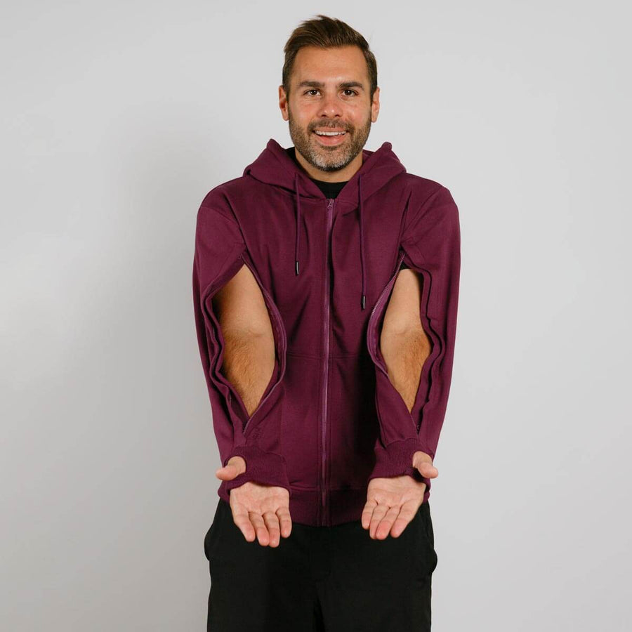Man wearing maroon zip hoodie with open side cutouts, displaying the garment's unique design features.
