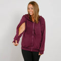 Woman wearing a burgundy zip hoodie with cutout sleeves over black leggings, smiling downward. | Model is 5'3" 130lbs wearing size S