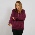 Woman wearing a burgundy zip-up hoodie and black pants, smiling while looking down.
