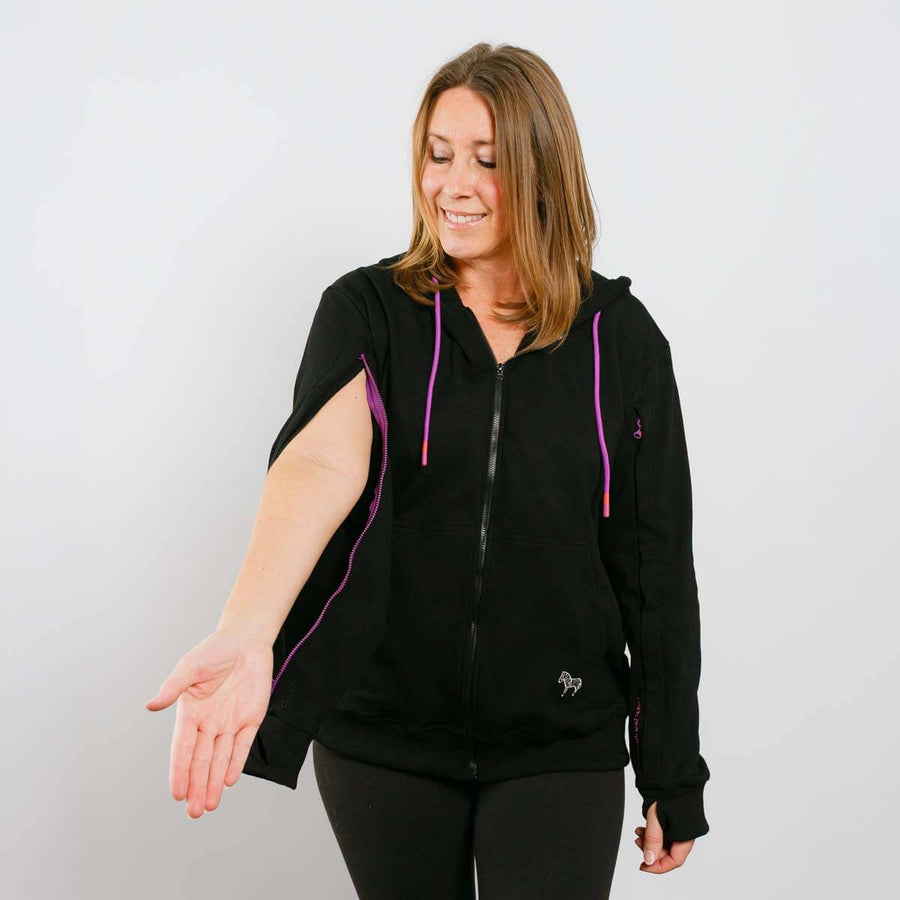 Woman wearing black IV zip hoodie with purple trim and side arm access zipper, front view.