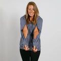 Woman wearing a slate blue zip hoodie with cutout sleeves over black pants, smiling at camera.
