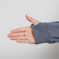 Hand extended from slate blue zip hoodie sleeve showing ribbed cuff detail against white background.