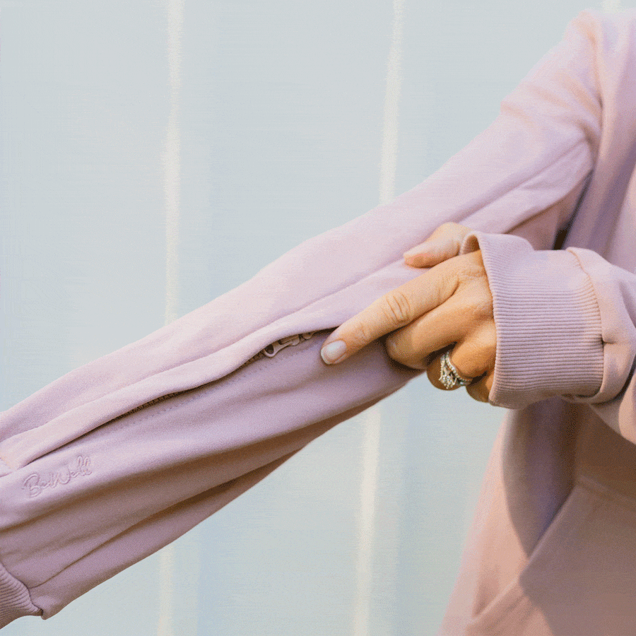 Woman wearing lavender IV zip hoodie with sleeve zipper open, displaying arm access feature.
