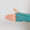 Person wearing a turquoise zip hoodie with their hand extended open against a white background.