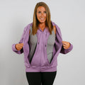 Woman wearing a lavender zip hoodie over a gray shirt with hands holding the hood open. | Model is 5'3" 130lbs wearing size S
