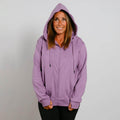 Woman wearing a lavender zip-up hoodie with hood up, smiling at camera against white background.