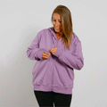 Woman wearing a lavender zip-up hoodie over black pants, smiling while zipping the jacket.