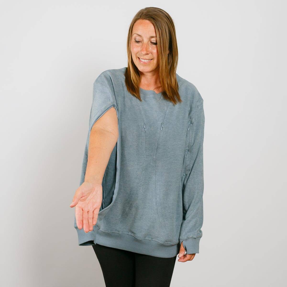 Woman wearing a blue-gray crewneck sweatshirt with an open side seam, paired with black pants.
