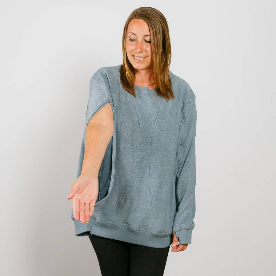 Woman wearing a blue-gray crewneck sweatshirt with an open side seam, paired with black pants.
