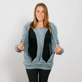 Woman wearing light blue zip-up crewneck sweatshirt over black shirt and black pants, smiling at camera. | Model is 5'3" 130lbs wearing size S