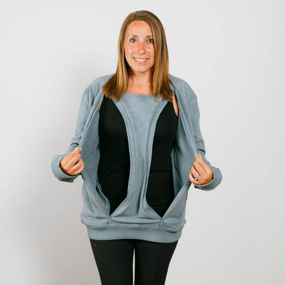Woman wearing light blue zip-up crewneck sweatshirt over black shirt and black pants, smiling at camera. | Model is 5'3" 130lbs wearing size S