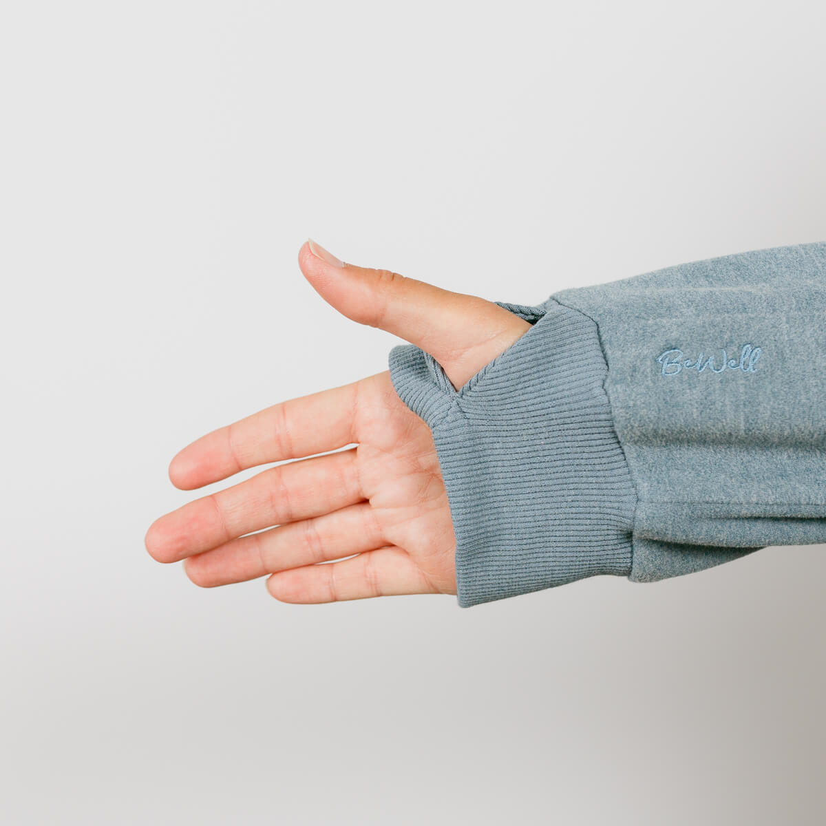 Hand extended from gray crewneck sweatshirt with ribbed cuff against white background.