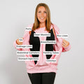 Woman in pink crewneck demonstrating labeled medical access points and devices on torso.