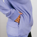 Person wearing light purple crewneck sweatshirt with hand visible through accessible side opening.