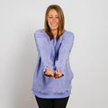 Woman wearing a light purple crewneck sweatshirt with thumbholes, smiling at the camera.