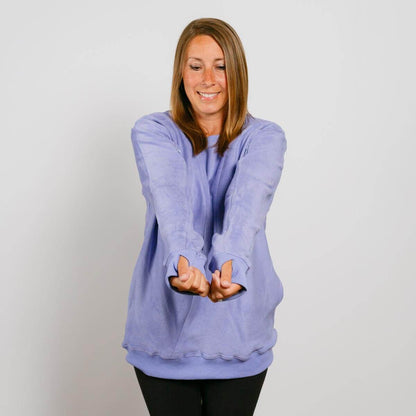 Woman wearing a light purple crewneck sweatshirt with thumbholes, smiling at the camera.