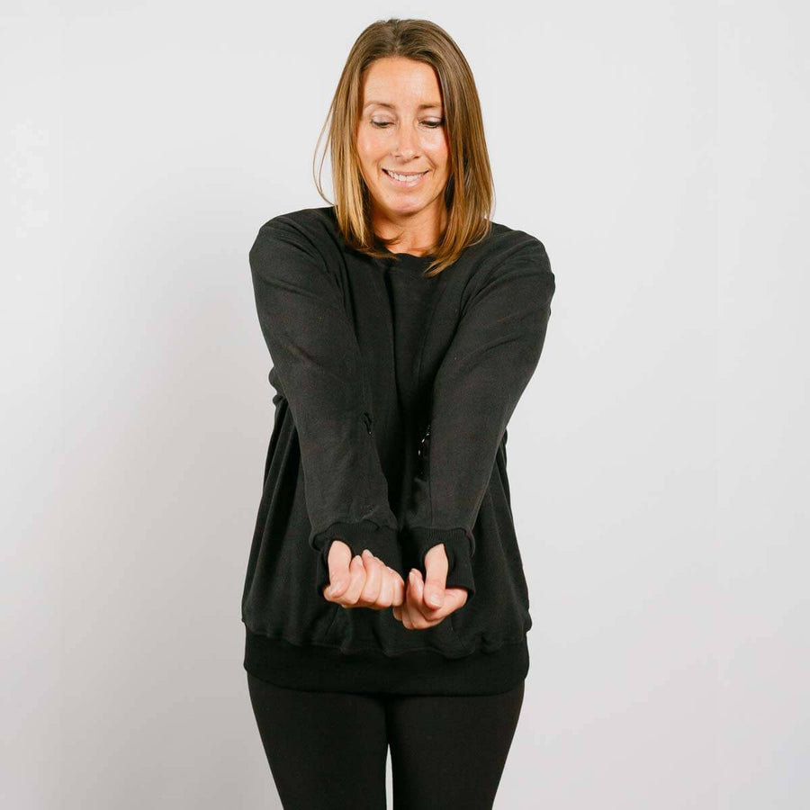 Woman wearing black multi-access crewneck with arms crossed in front view.