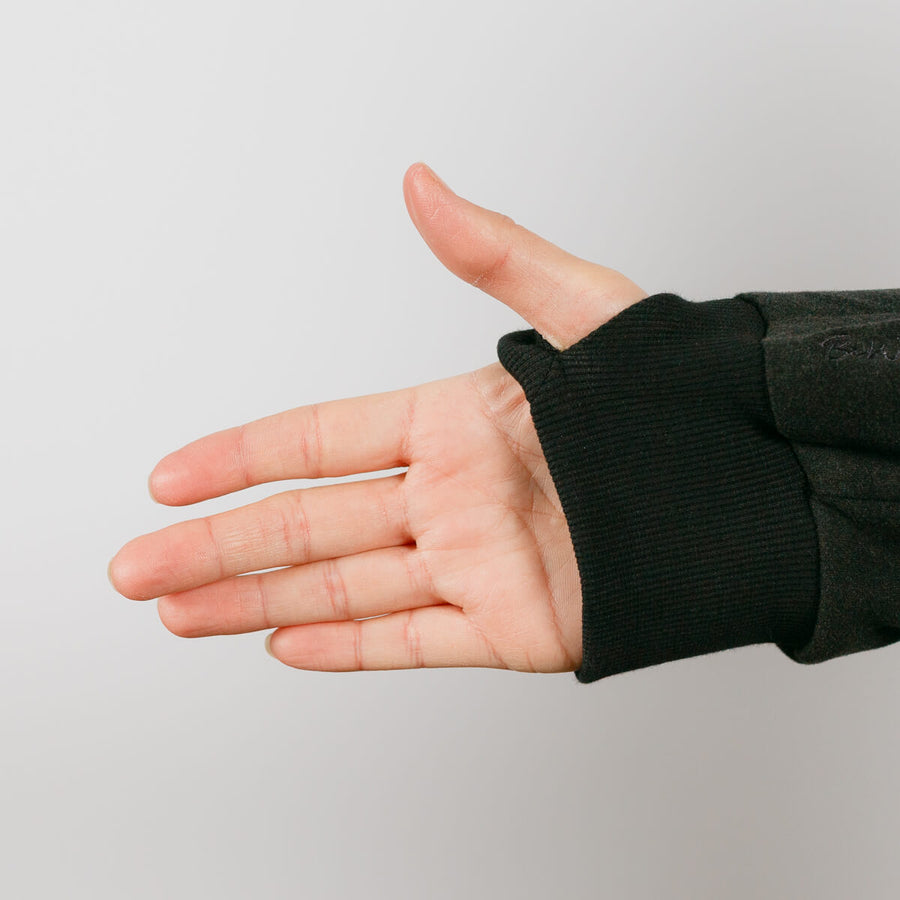 Person wearing black crewneck with arm extended showing access port opening detail.