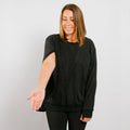Woman wearing black crewneck with left side zipper access feature visible.