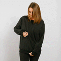 Woman wearing black multi-access crewneck with thumb holes, front view.