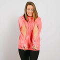 Woman wearing pink hoodie with open side panels and black leggings, smiling at camera.