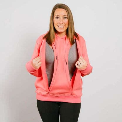 Woman wearing pink zip-up hoodie over gray shirt with black pants, smiling at camera. #NEW Multi-Access Hoodie Flamingo | Model is 5'3" 130lbs wearing size S