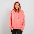 Woman wearing a bright coral pink hoodie with drawstrings and black pants against a white background.