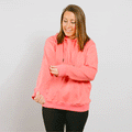 Woman wearing a bright pink zip-up hoodie over black pants against a white background.