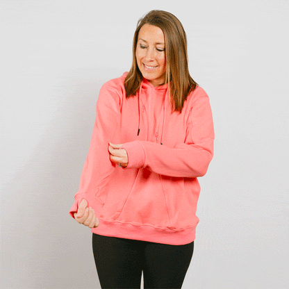 Woman wearing a bright pink zip-up hoodie over black pants against a white background.