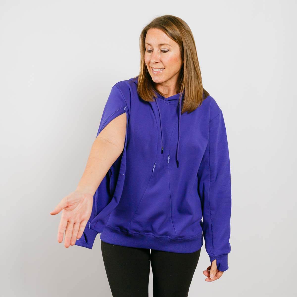 Woman wearing a blue hoodie with short sleeves and black pants, demonstrating the garment's fit.