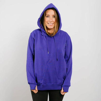 Woman wearing a purple hoodie with drawstrings and black pants against a white background.