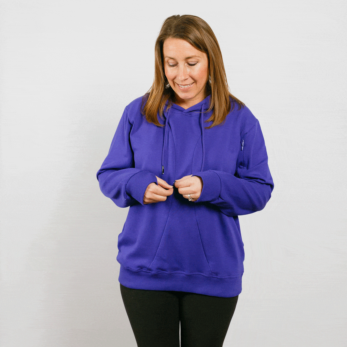 Woman wearing a bright blue hoodie with drawstrings and black pants against a white background.