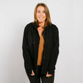 Woman wearing black zip hoodie with gold shirt underneath, front view showing accessible design.