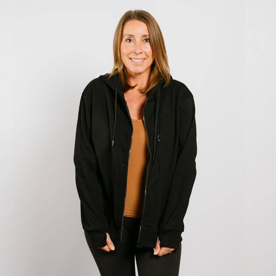 Woman wearing black zip hoodie with gold shirt underneath, front view showing accessible design.