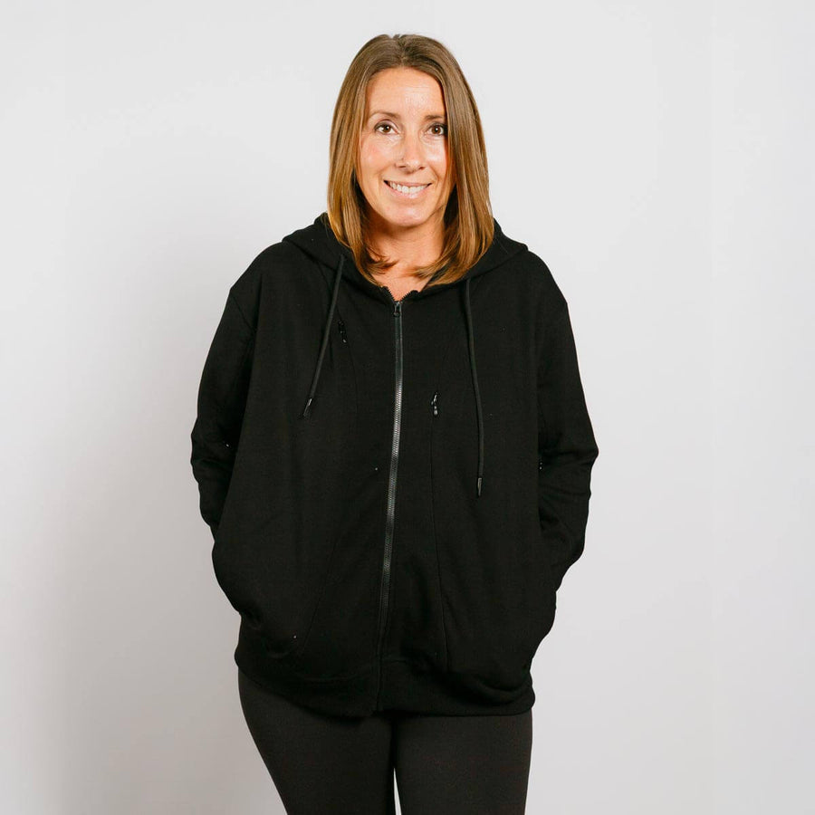 Woman wearing black zip hoodie with front access zipper, standing against neutral background.