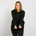 Woman wearing black zip hoodie with visible arm access zippers, smiling at camera in front view.