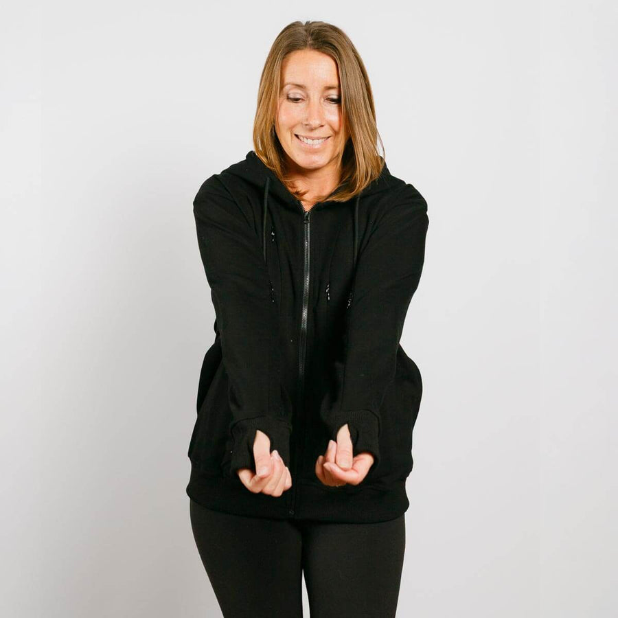 Woman wearing black zip hoodie with visible arm access zippers, smiling at camera in front view.