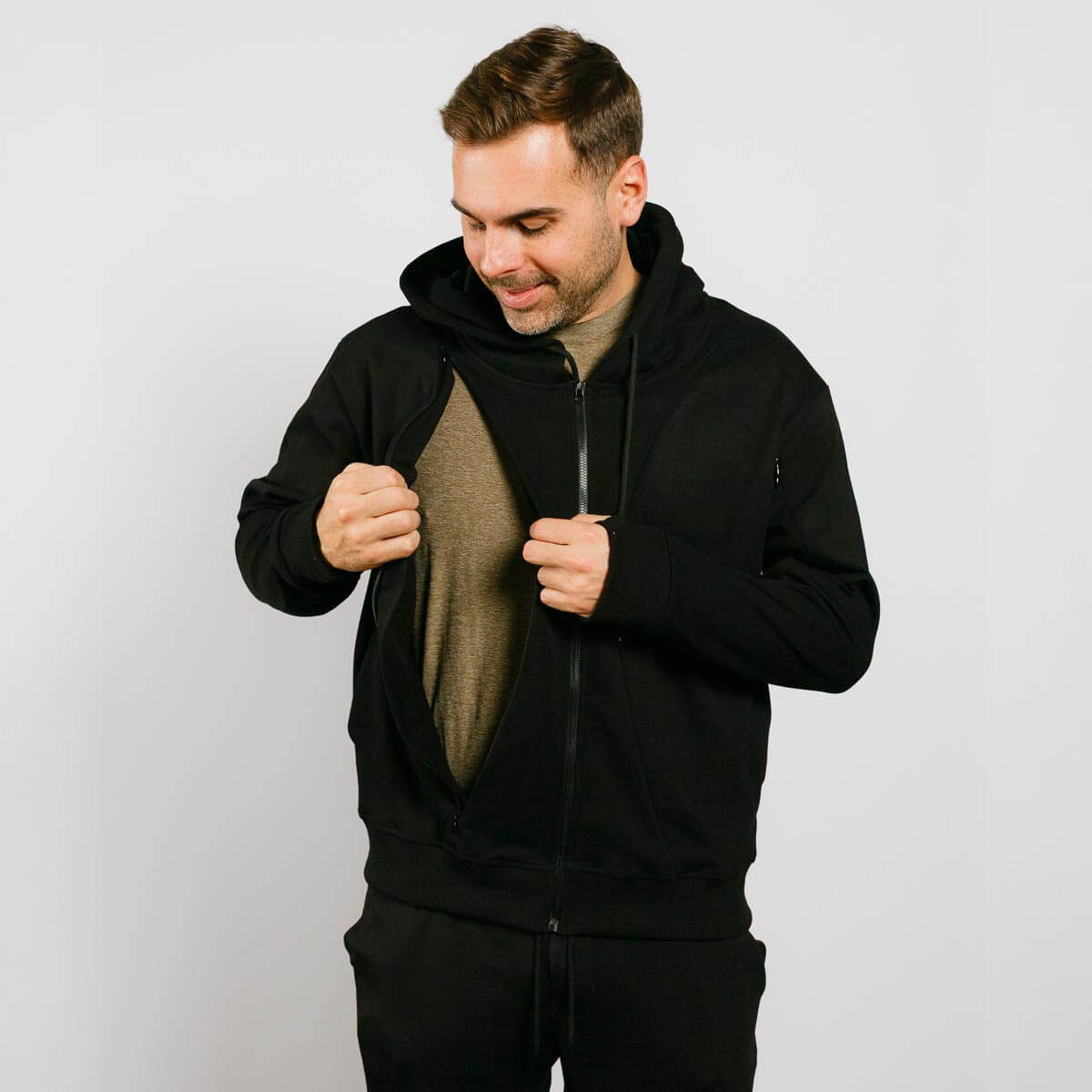 Man wearing a black hoodie with a plain background | Model is 5'8" 165lbs wearing size M