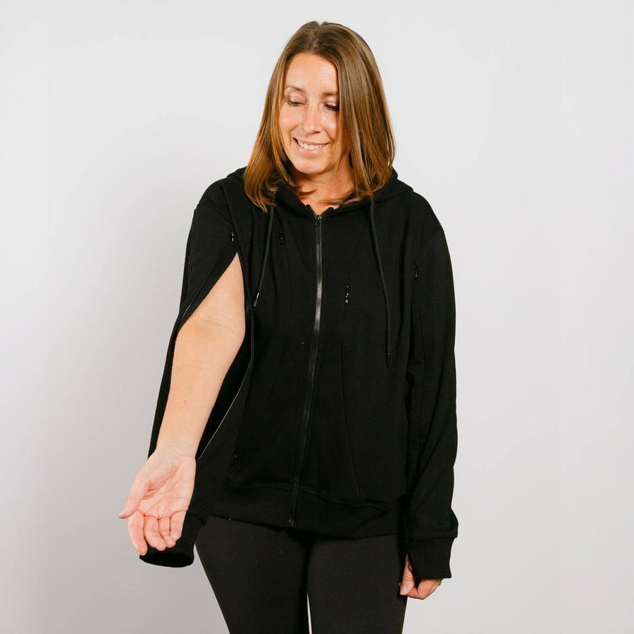 Woman wearing black zip hoodie with left sleeve access zipper partially open.