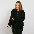 Woman wearing black zip hoodie with left sleeve access zipper partially open during treatment.