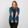 Woman wearing navy blue zip hoodie with cutout sleeves over black pants, smiling at camera.