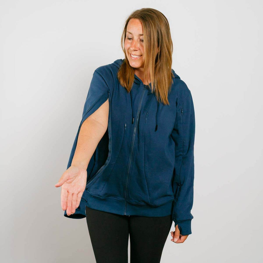 Woman wearing navy blue zip-up hoodie with black pants against white background.