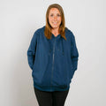 Woman wearing a navy blue zip-up hoodie with black pants, smiling at camera.