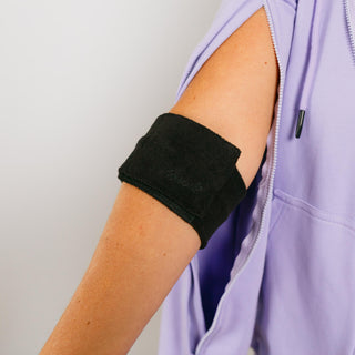 Person wearing a black over it wrap on a plain background  | Model’s arm is 10.5" around and wearing size M